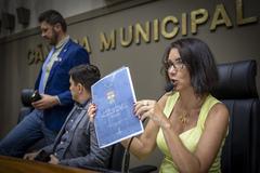 Movimentação de plenário. Presidente Comandante Nádia distribui versão impressa da Lei Orgânica do Município.