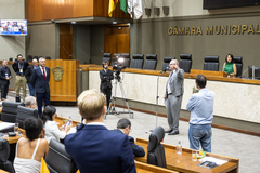 Movimentação de plenário. Vereador Tiago Albrecht no microfone de apartes