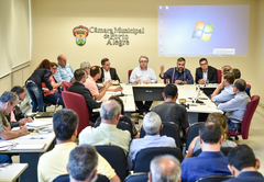 Informações sobre cumprimento da Lei dos Táxis. Representantes da EPTC e associações de taxistas na mesa e platéia.