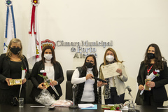 Vereadora Cláudia Araújo (c) entrega diploma à diretora Regina Teixeira