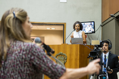 Movimentação de plenário. Vereadora Karen Santos na tribuna e vereadora Mônica Leal no microfone de apartes.